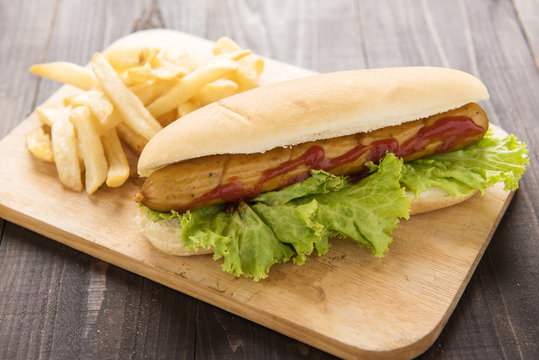 Hot dog with french fries on wooden background.