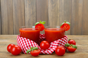 Glasses of tomato juice with vegetables on wooden background