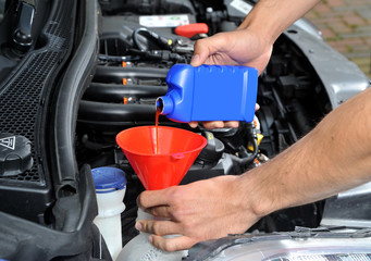 Pouring radiator leak repair liquid into a car cooling system