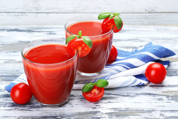 Glasses of tomato juice with vegetables on wooden background