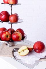 Tasty ripe apples on serving tray on brick wall background