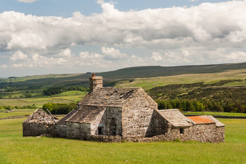 derelict barn on grassy meadow