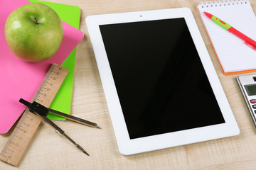 Tablet and school supplies on wooden table, closeup