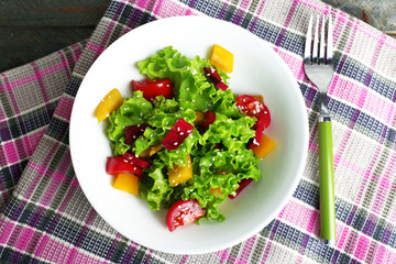 Bowl of fresh green salad on table with napkin, closeup