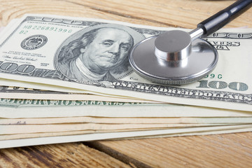 Financial analysis, audit or accounting - Stethoscope over dollar bills on wooden table. Medical...