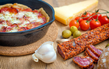 Top view of pizza in iron pan with ingredients.