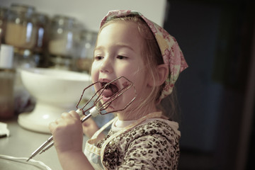 Little girl licking chocolate off the mixer beater