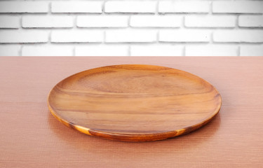 Empty round wooden tray on table over white brick wall backgroun