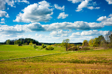 Fototapeta na wymiar Countryside field and road, blue sky clouds