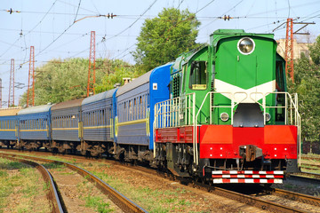 Green locomotive and blue passenger cars.