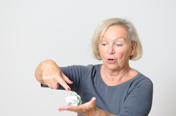 Ältere Frau hält zerknitterten Geldschein in der Hand