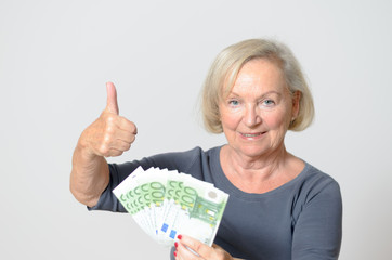 Ältere Frau hält einen Fächer von Banknoten