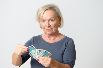 Senior Woman Holding Tarot Cards Against Gray Wall - obrazy, fototapety, plakaty