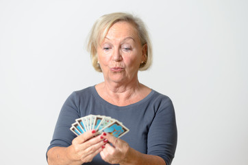 Seniorin hält Spielkarten in der Hand - obrazy, fototapety, plakaty