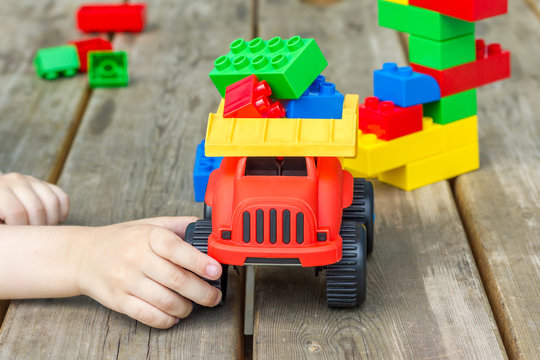 Child Playing With Toy Truck And Plastic Building Blocks