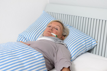 Kranke Frau mit Fieber im Bett