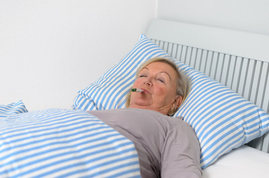 Kranke Frau mit Fieber im Bett