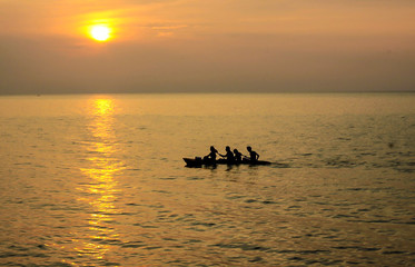 Four men in a boat at sunset