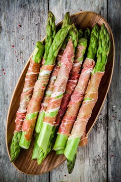 Fresh organic asparagus wrapped in Parma ham on a bowl