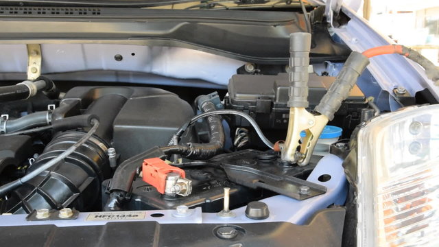 automotive technician charging vehicle battery