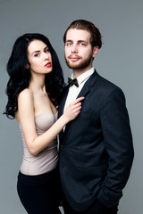 Handsome man in suit and pretty brunette female model on grey background