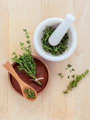Bunch of fresh organic thyme in white mortar on wooden backgroun