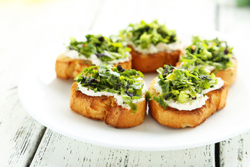 Tasty fresh bruschetta on plate on white wooden background