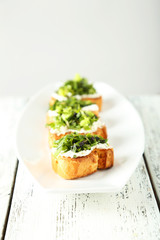 Tasty fresh bruschetta on plate on white wooden background