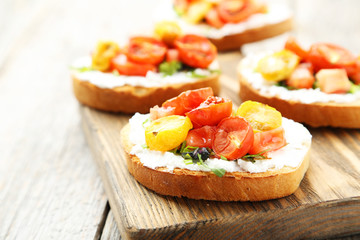 Tasty fresh bruschetta with tomatoes on cutting board on grey wo