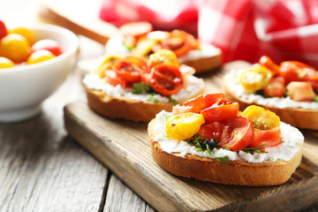 Tasty fresh bruschetta with tomatoes on cutting board on grey wo