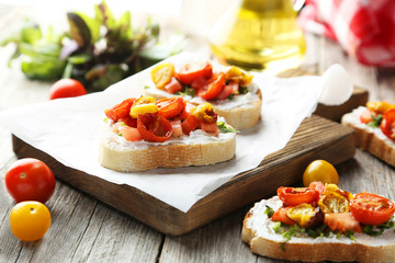 Tasty fresh bruschetta with tomatoes on cutting board on grey wo