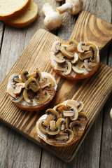 Tasty fresh bruschetta with mushrooms on cutting board on grey w