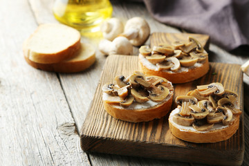 Tasty fresh bruschetta with mushrooms on cutting board on grey w