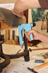 An upholsterer repairing an armchair with stapler