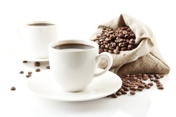 Cups of coffee with saucer with bag with coffee beans on white