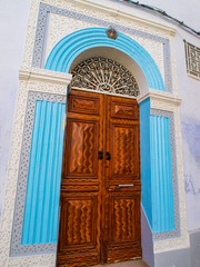 Ornate carved wooden door surrounded by blue stinework in the me