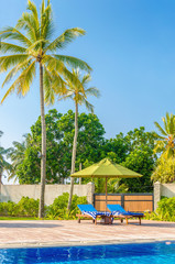 Romantic view of two sunbeds at swimming pool 