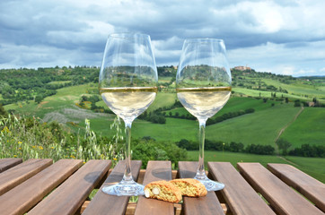White wine and cantuccini on the wooden table against Tuscan lan