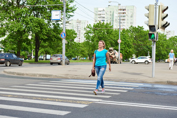 Young woman crossing road at green light
