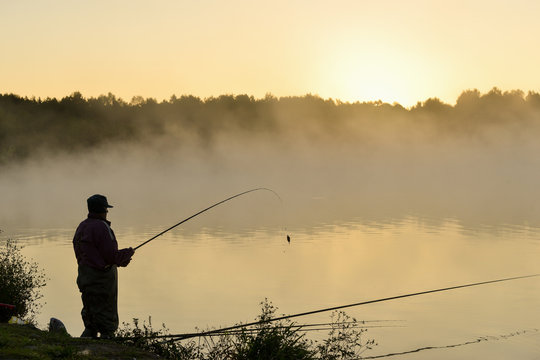 Fisherman catches fish on the lake at sunset