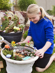 Young girl helping to make fairy garden in a flower pot