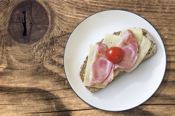 Plate with Ham Cheese and Tomato Sandwich on Wood.