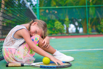 Little girl trying to play tennis on outdoor court