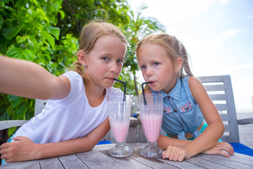 Little girls taking selfie and drinking tasty cocktails at