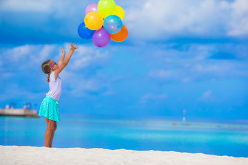 Adorable little girl playing with colorful balloons at tropical