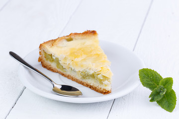 Tasty slice of rhubarb pie on white wooden table.
