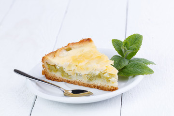 Tasty slice of rhubarb pie on white wooden table.