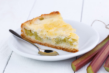 Tasty slice of rhubarb pie on white wooden table.