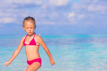 Adorable happy little girl have fun at shallow water on beach