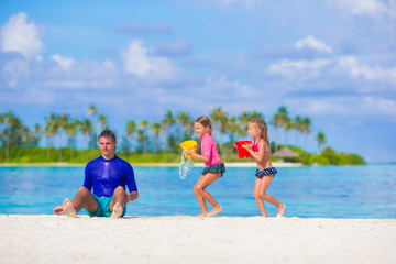 Cute little girls and father having fun with beach toys on